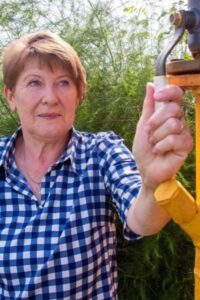 alt="Жительница частного дома в Омской области проверяет газовый кран после подключения к магистрали"