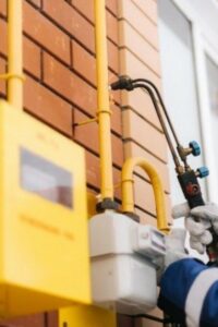 alt="Специалист ogs55.ru устанавливает и проверяет газовое оборудование на фасаде частного дома"