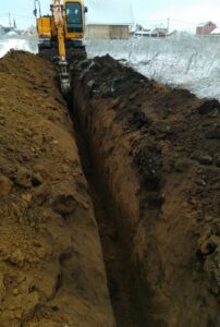 alt="Копка траншеи для прокладки газопровода экскаватором в зимний период в Омской области"